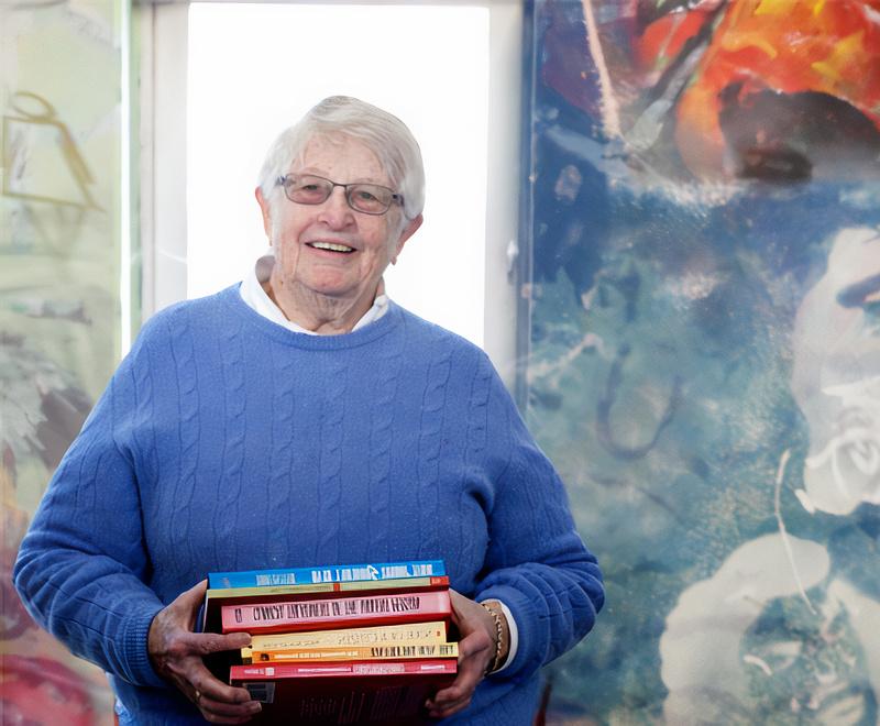 Portrait of Wiggsy Sivertsen with lightblue sweater holding a stack of books.